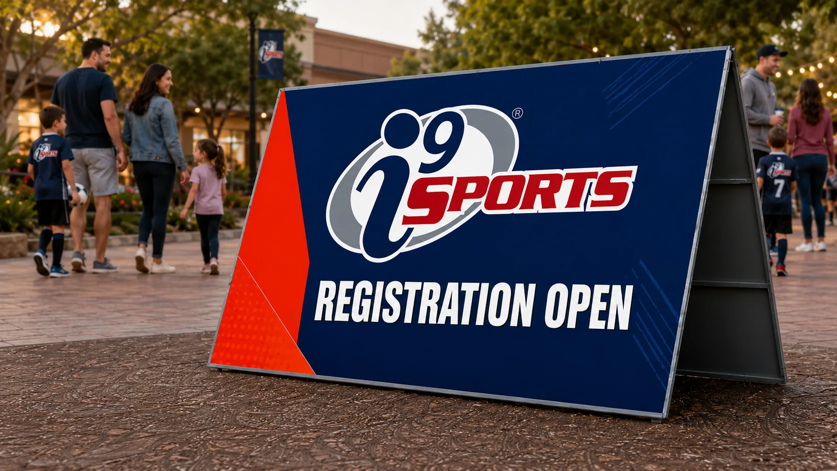 i9 Sports registration open A-frame sign with families nearby
